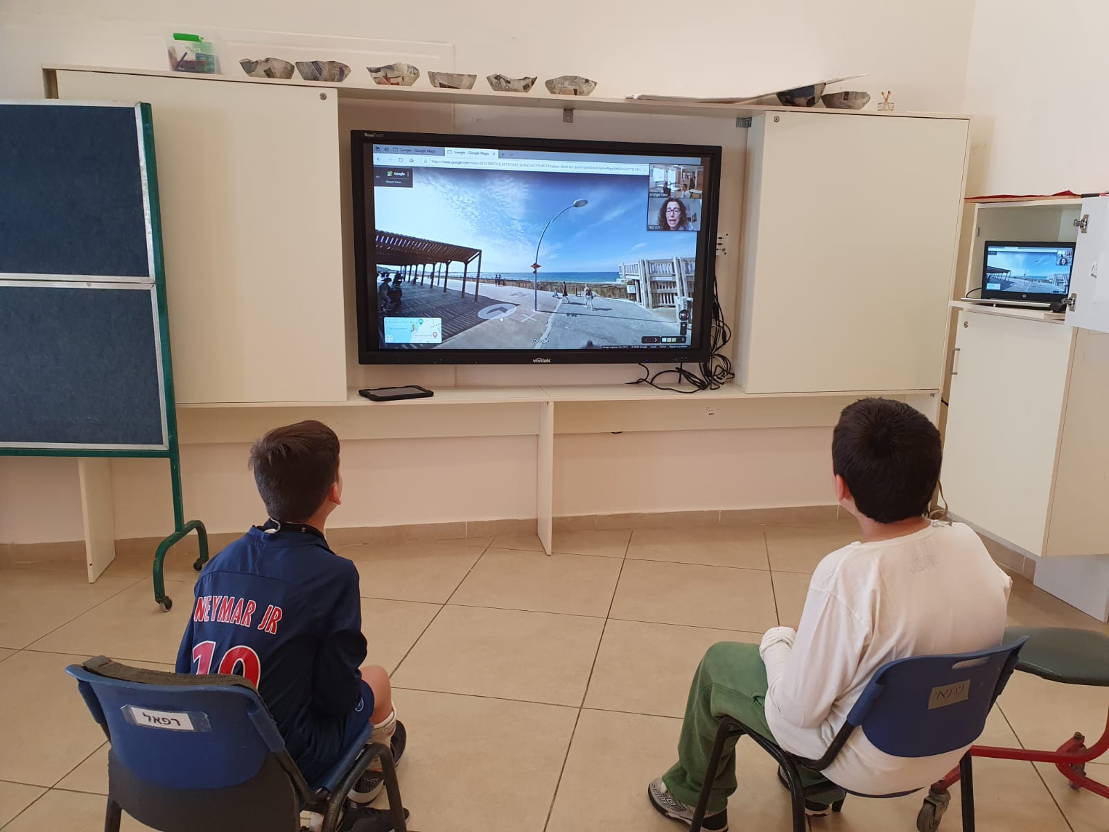 Students in a classroom watching something on a big screen